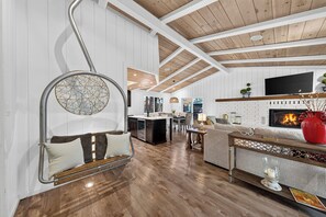 A spacious living area with a fireplace, a kitchen in the background, and a dining area. - South Lake Tahoe • Fireplace + Pine-View Deck + Trail Access | Timberlight (South Lake Tahoe)
