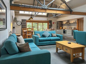 A modern living room with a sofa, a wooden coffee table, and a dining area with a table and chairs. - The Coach House - UKC10037 (St Andrews)