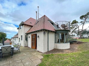 A two-story house with a red-tiled roof, a wooden door, and a small balcony with a railing. - Lady Bluebell - UKC10036 (St Andrews)