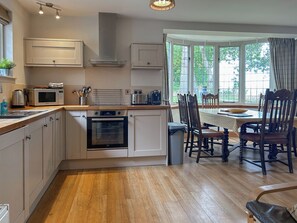 Een moderne keuken met oven, magnetron en een eethoek met houten stoelen en een tafel.