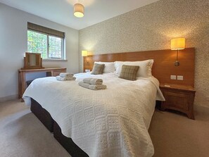 A neatly made bed with a headboard, two bedside lamps, and a window with a view of greenery. - Lady Bluebell - UKC10036 (St Andrews)