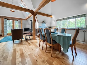A spacious dining area with a wooden table and chairs, a television, and a view of the outdoors through large windows. - The Giddy Limit Cottage - UKC10039 (St Andrews)