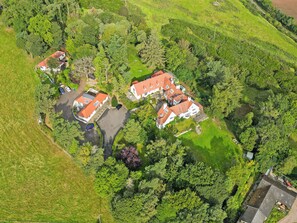 Vista aèria d'una zona residencial amb diverses cases, una àrea de pàrquing i vegetació als voltants.