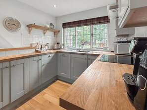 A kitchen with grey cabinets, a wooden countertop, a window with a view, and a Bosch coffee maker. - Baillie Scott Cottage - UKC10041 (St Andrews)