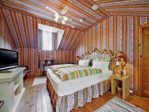Ein Schlafzimmer mit einem Bett, einem Schreibtisch, einem Fernseher und einem Deckenventilator.