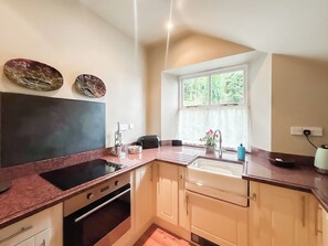 A kitchen with a built-in oven, a sink, and a window providing natural light. - 1 bedroom accommodation in Bishops Castle (Bishops Castle)