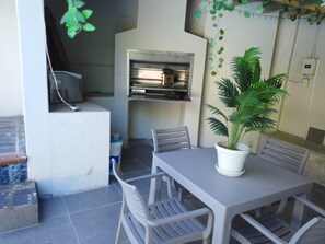 A dining area with a table and chairs, a potted plant, and a kitchen area with cabinets and a microwave. - Luxurious 6-Bedroom House with Private Facilities in Ugu District (Ugu District Municipality)