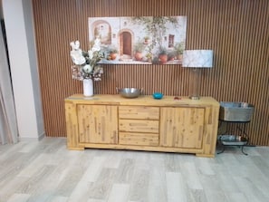 A wooden cabinet with drawers, a vase with flowers, a metal bowl, and a wall-mounted shelf with a picture. - Luxurious 6-Bedroom House with Private Facilities in Ugu District (Ugu District Municipality)