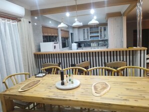 Ein Essbereich mit Holztisch, Stühlen und einer Küche im Hintergrund.