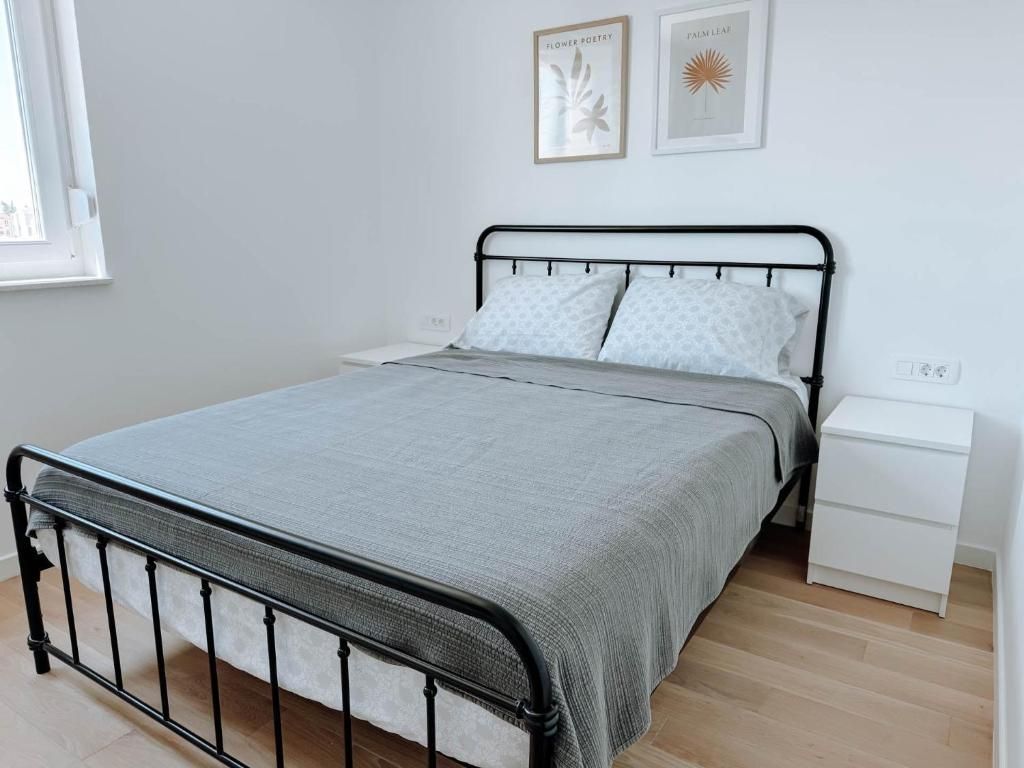 Une chambre à coucher comprenant un lit, une table de chevet, un interrupteur fixé au mur et deux tableaux encadrés.