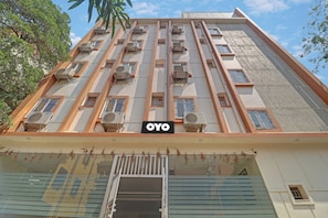 Un immeuble à plusieurs étages doté d’une entrée centrale, de climatiseurs à chaque étage et d’une enseigne portant le mot « OYO ».
