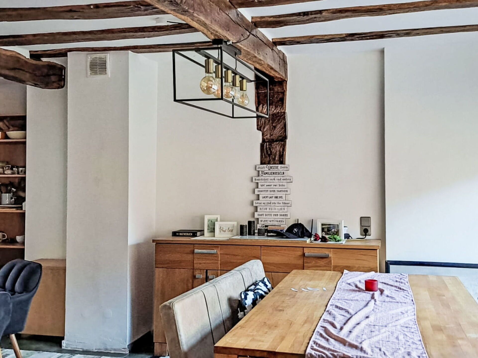 Un comedor con una mesa de madera, sillas y una estantería.