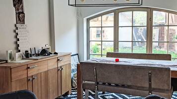 A dining area with a table and chairs, a wooden cabinet, and a window with a view of greenery.
