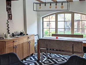 A dining area with a table and chairs, a wooden cabinet, and a window with a view of greenery.