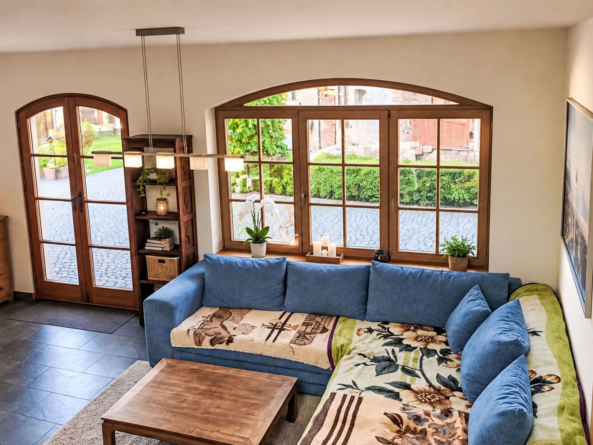 Un salón con un sofá azul, una mesa de centro de madera y vistas a través de amplios ventanales.