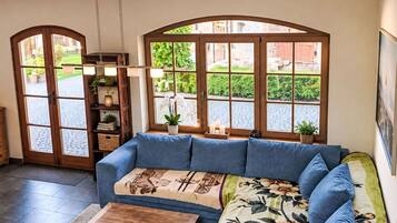 Un salón con un sofá azul, una mesa de centro de madera y vistas a través de amplios ventanales.