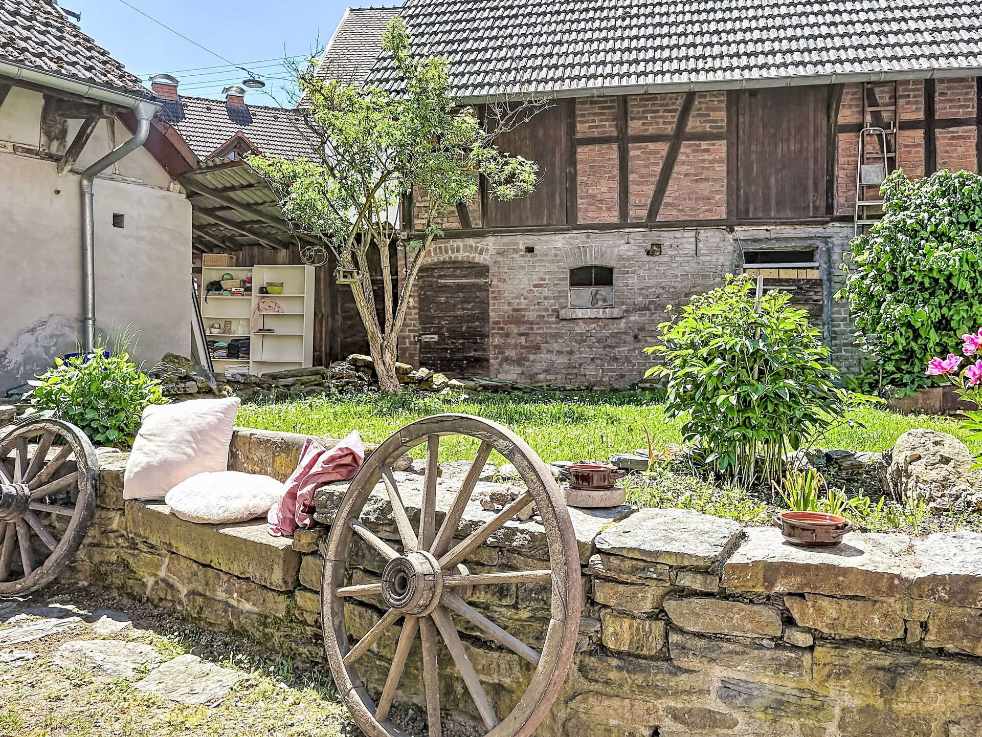 Ein rustikales Gebäude mit Steinmauer, Hollegetüren und einem kleinen Garten.