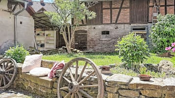 Ein rustikales Gebäude mit Steinmauer, Hollegetüren und einem kleinen Garten.