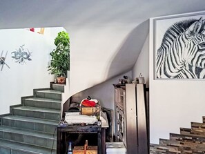 Eine Treppe mit einem Blumentopf links, einem gerahmten Kunstwerk rechts und einem unordentlichen Tisch in der Mitte.