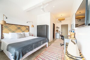 Habitación de hotel moderna con cama, escritorio, armario y baño visible a través de una puerta abierta.