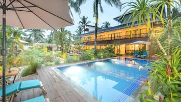 A pool area with lounge chairs and a thatched-roof structure.