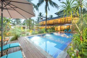 A pool area with lounge chairs and a thatched-roof structure.