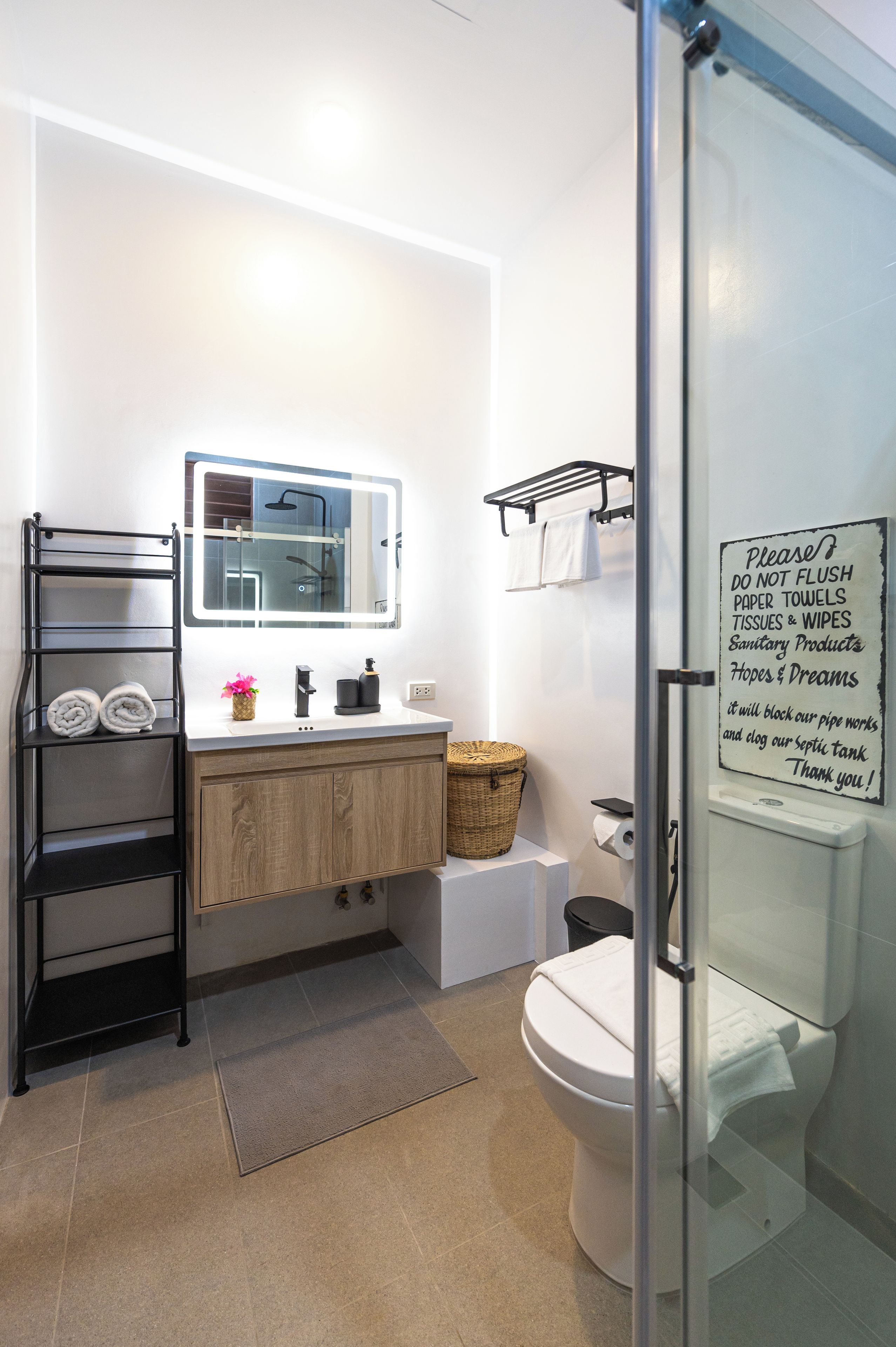 Ein modernes Badezimmer mit einer Duschkabine aus Glas, einem Waschbecken inklusive Spiegel und einer Toilette.