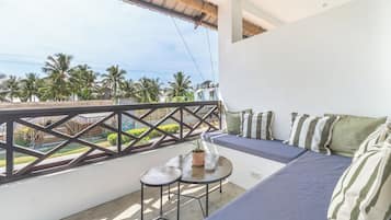 A balcony with a seating area, a small table, and a potted plant.
