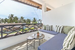 A balcony with a seating area, a small table, and a potted plant. - Kalipay Resort Siargao (General Luna)
