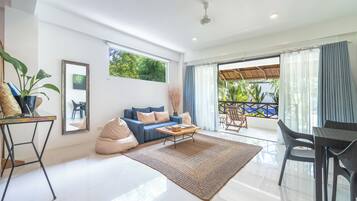 A modern living room with a sofa, coffee table, and a view to a balcony.
