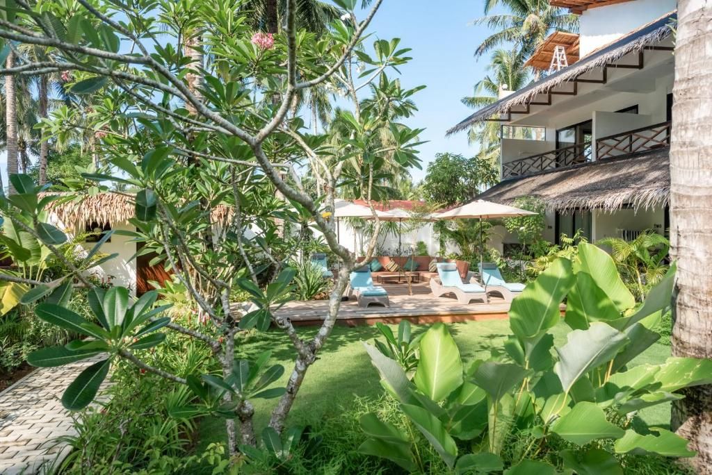 A tropical resort with a pool area, lounge chairs, and lush vegetation.