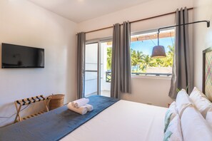 Una habitación de hotel con cama, televisión de pantalla plana, vista a palmeras y balcón.