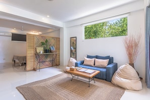 Sala de estar moderna com sofá, mesa de centro e uma janela grande com vista para o verde.