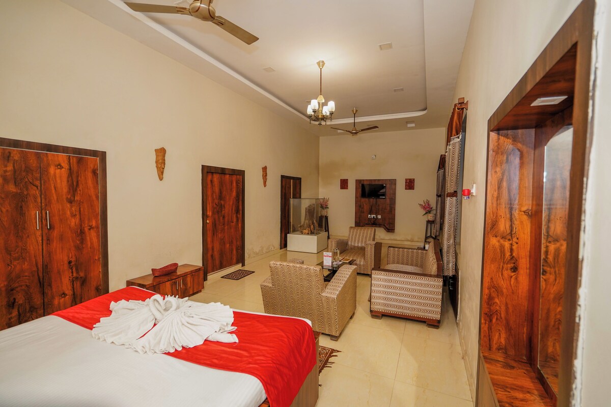 Una habitación de hotel con cama, escritorio, silla, televisor y ventilador de techo.