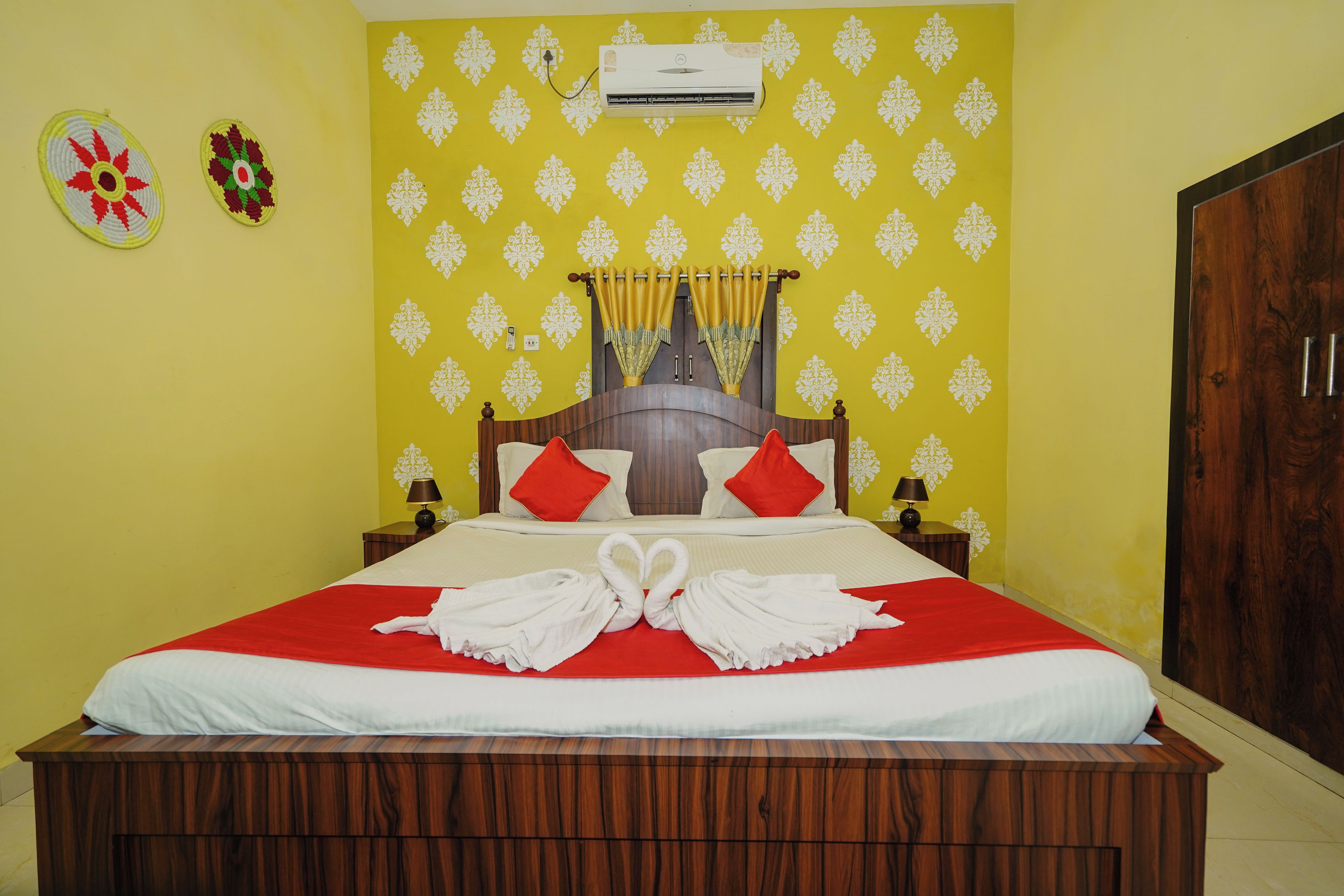 Una habitación de hotel con una cama, un armario de madera, un aire acondicionado de pared y un papel tapiz amarillo con estampado.