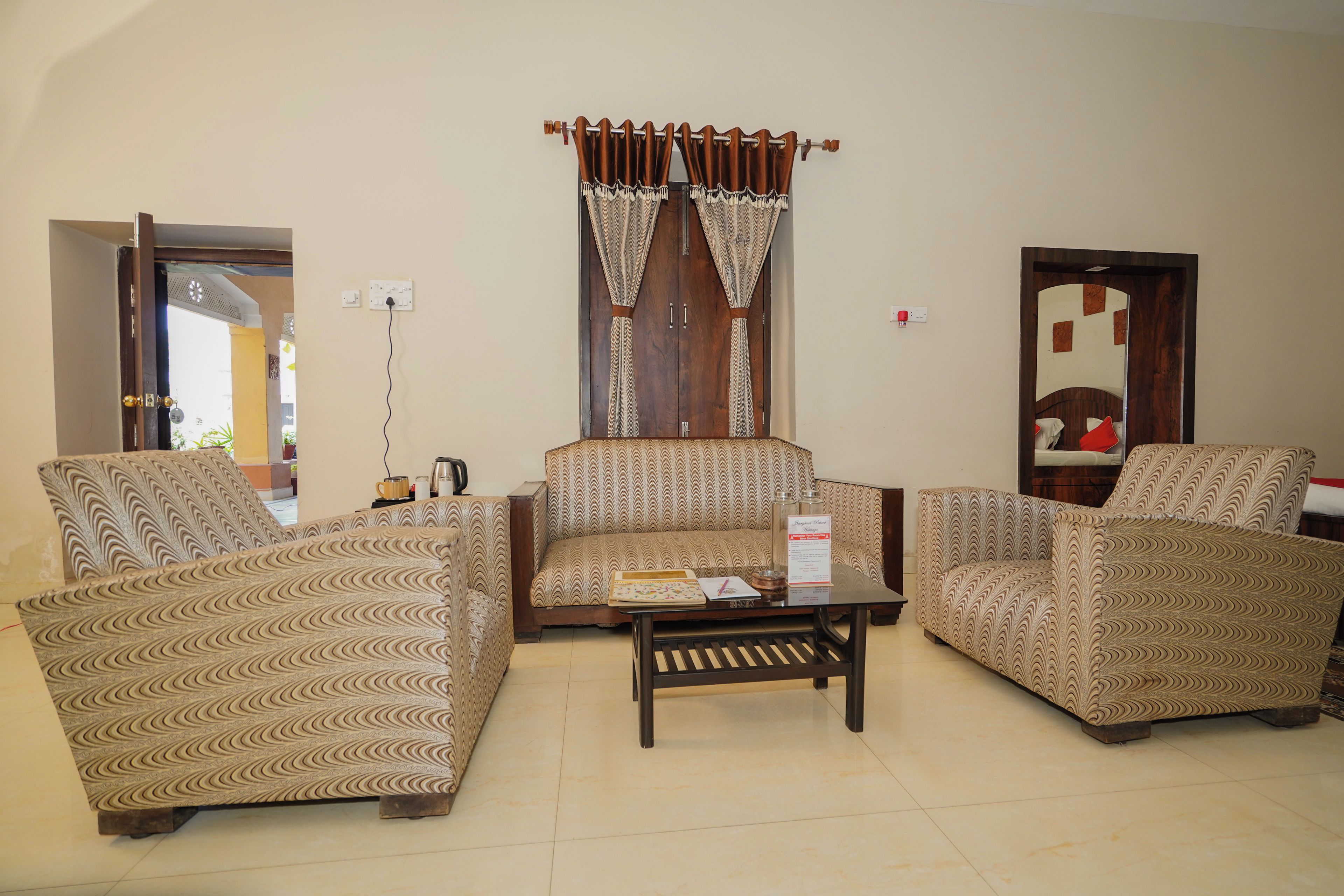 A living room with patterned sofas, a coffee table, and a window with curtains.