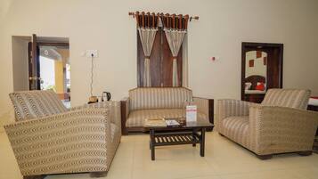 A living room with patterned sofas, a coffee table, and a window with curtains.