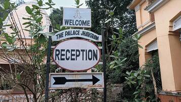 A signpost with 'WELCOME THE PALACE JHARGAM' and 'RECEPTION' indicating the direction to the reception area.