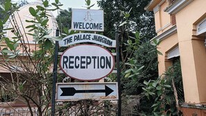Un cartel con la inscripción 'WELCOME THE PALACE JHARGAM' y 'RECEPTION' que indica el camino a la recepción.