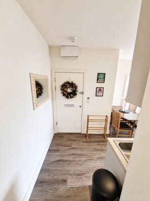 A hallway with a door, a wreath, and a small table with chairs. - Contemporary Cabot Circus Central Flat | Sleeps 4 (Saint Paul's)