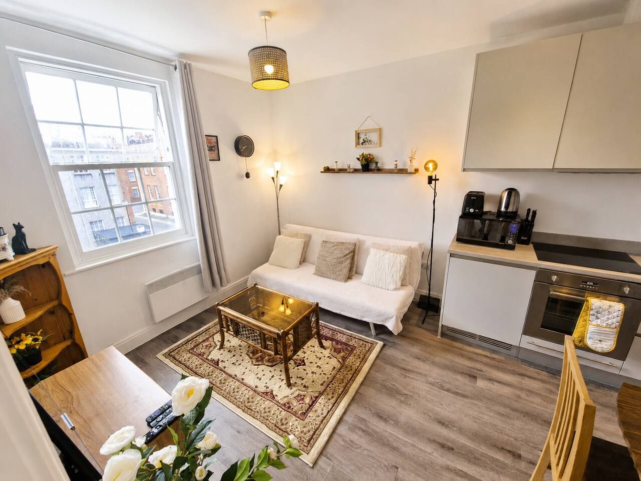 Een moderne woonkamer met een bank, salontafel en een uitzicht op de stad door een groot raam.