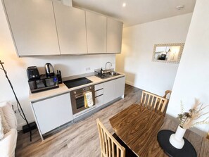 A compact kitchen with a dining area, featuring a microwave, coffee maker, and a sink. - Contemporary Cabot Circus Central Flat | Sleeps 4 (Saint Paul's)