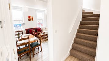 Eine Treppe führt zu einem Essbereich mit Holzboden und einem roten Sofa.