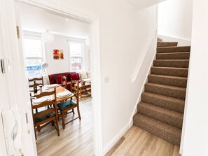 Un escalier menant à une salle à manger dotée d’un plancher en bois et d’un canapé rouge.