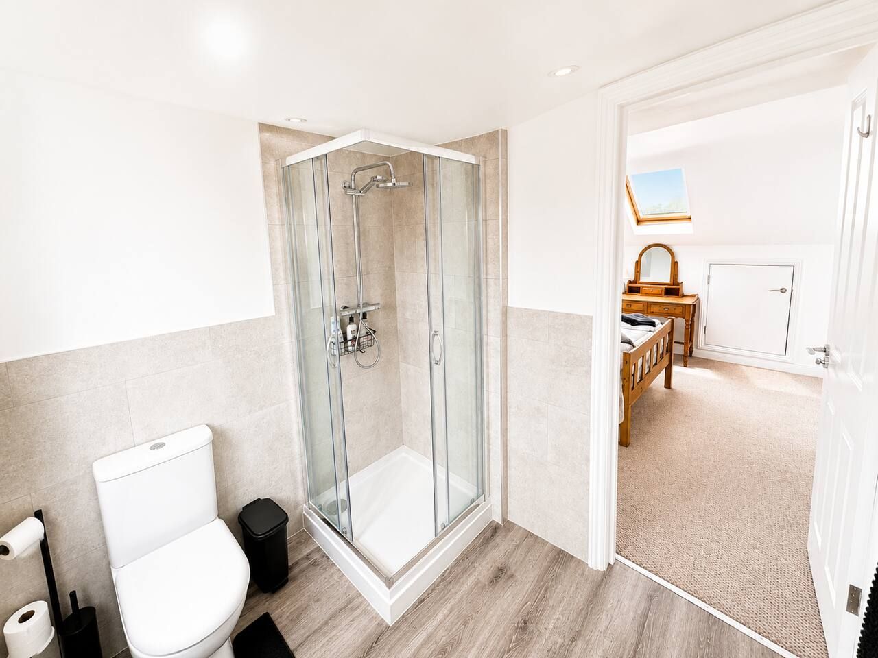 Een moderne badkamer met een douchecabine, toilet en wastafel.