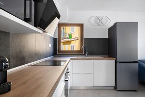 Eine moderne Küche mit Einbauofen, Edelstahlkühlschrank und Arbeitsplatte aus Holz.