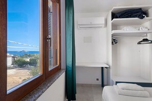 Ein Zimmer mit Fenster, einem Bett, einem Kleiderschrank und einer Kleiderstange.