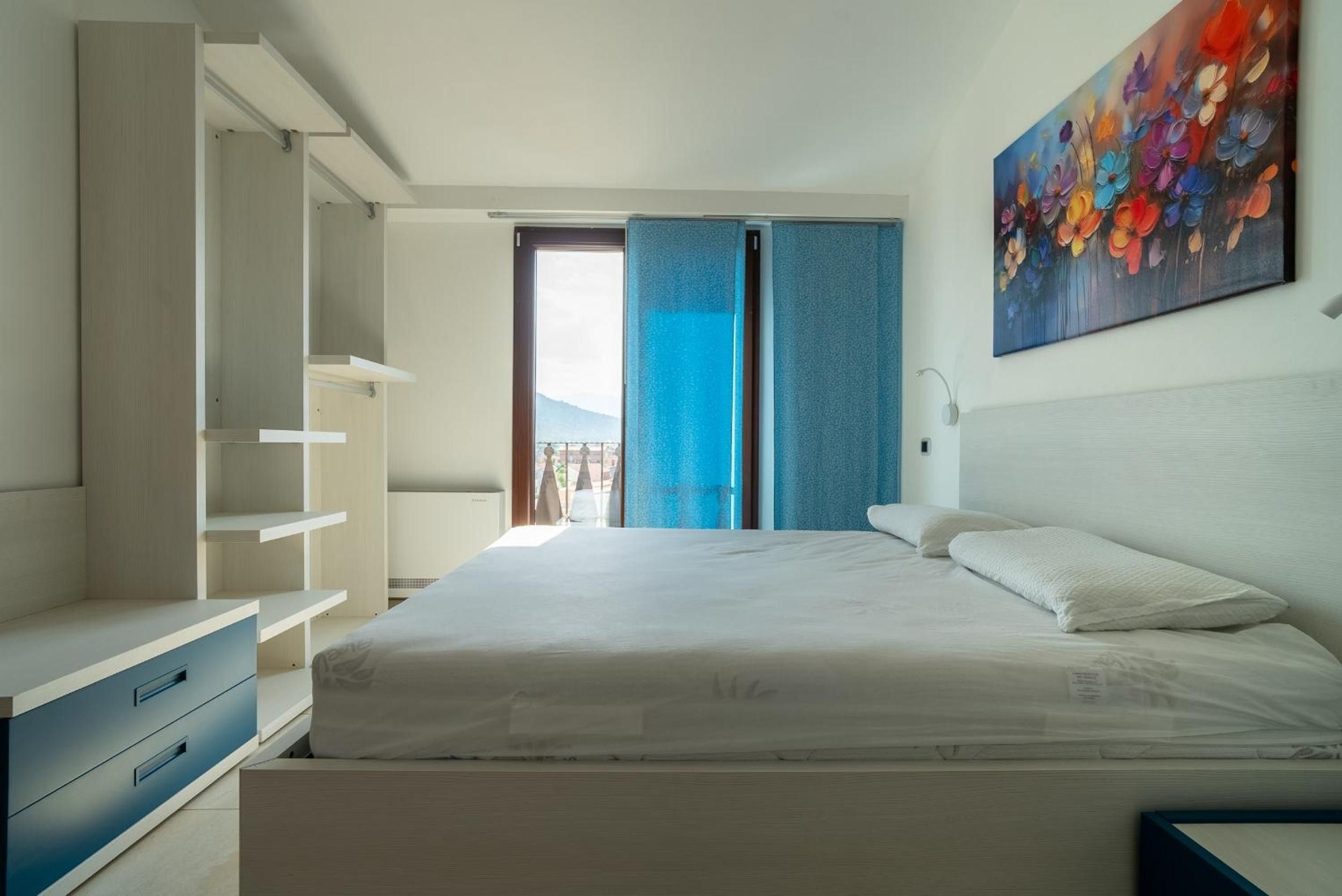 A bedroom with a bed, a wardrobe, and a painting on the wall.