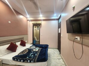 A hotel room with a bed, a television, and a bathroom visible through an open door. - Oly Hotel Heritage Inn (New Delhi)