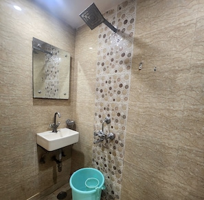 A bathroom with a sink, mirror, shower, and decorative tile wall. - Oly Hotel Heritage Inn (New Delhi)